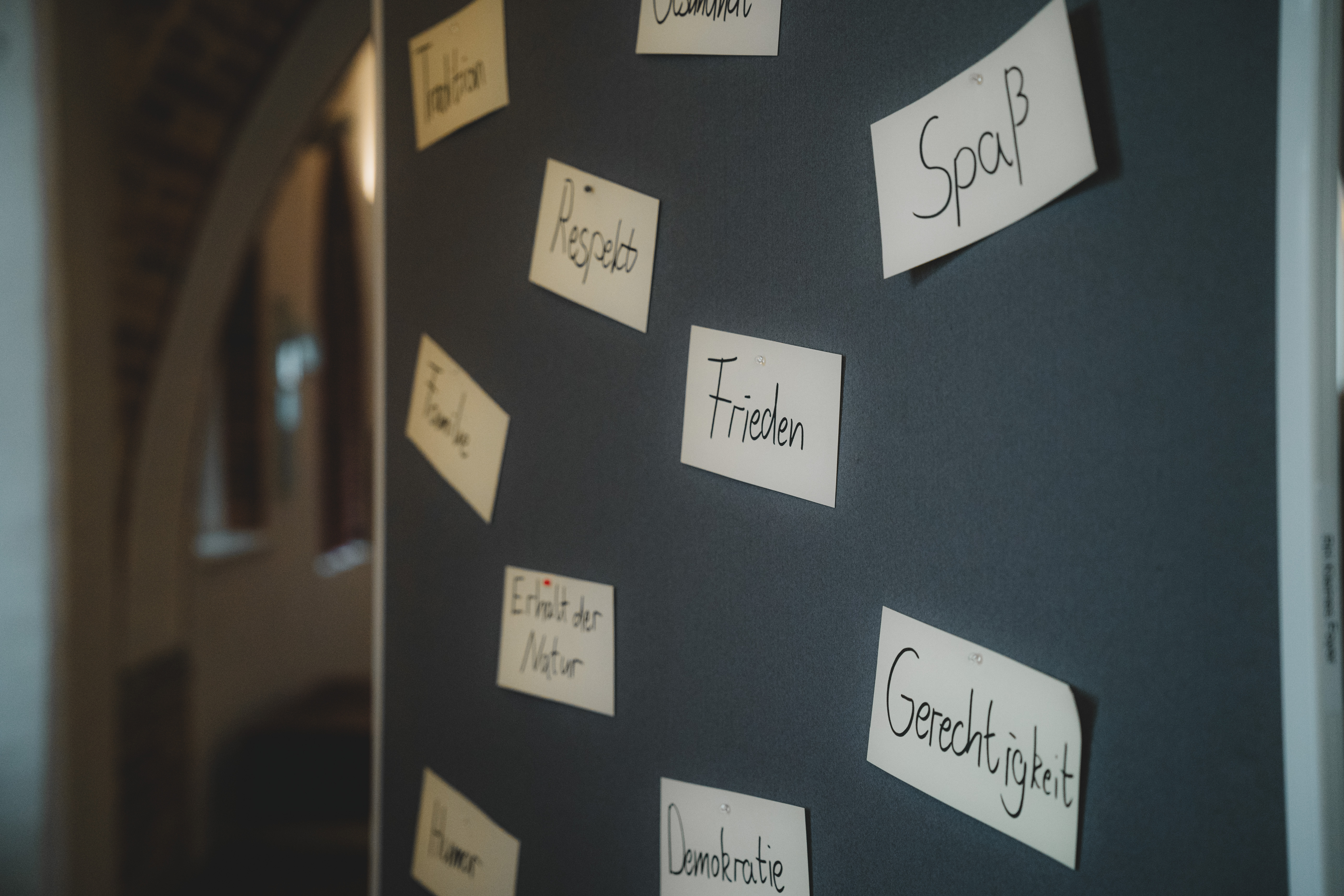 Beschriftete Moderationskarten an einer Pinnwand. Auf den Karten stehen Werte: Tradition, Familie, Respekt, Spaß, Frieden, Erhalt der Natur, Gerechtigkeit, Demokratie, Humor.
