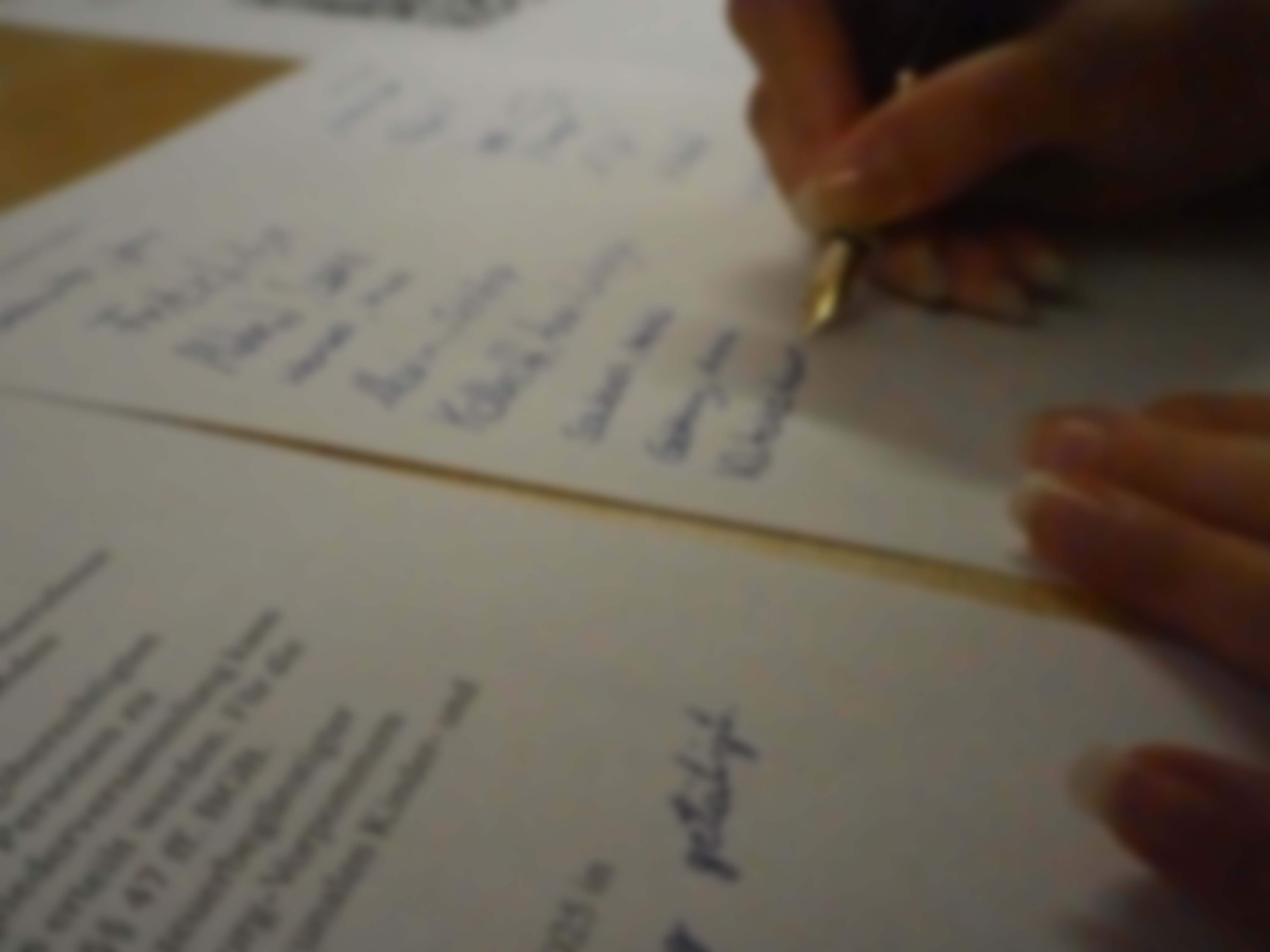 Ein Zettel mit Unterschriften. Eine Hand mit Stift ist zu sehen, die eine weitere Unterschrift setzt.